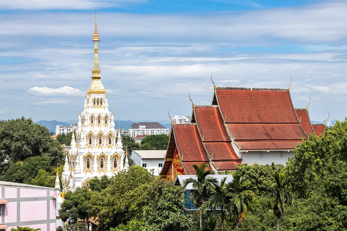 The white chedi of Wat Santitham above the rooftops