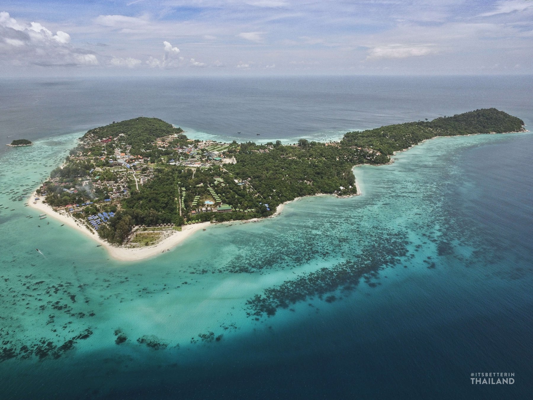Drone shot of Koh Lipe, with a long white-sand beach and coral reef showing through clear turquoise water
